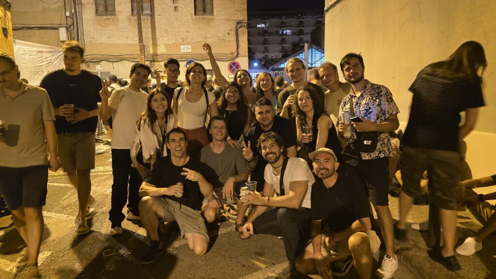 International group at the first night of Festa Major de Sants 2025 in Barcelona, enjoying music, drinks, and street celebrations.