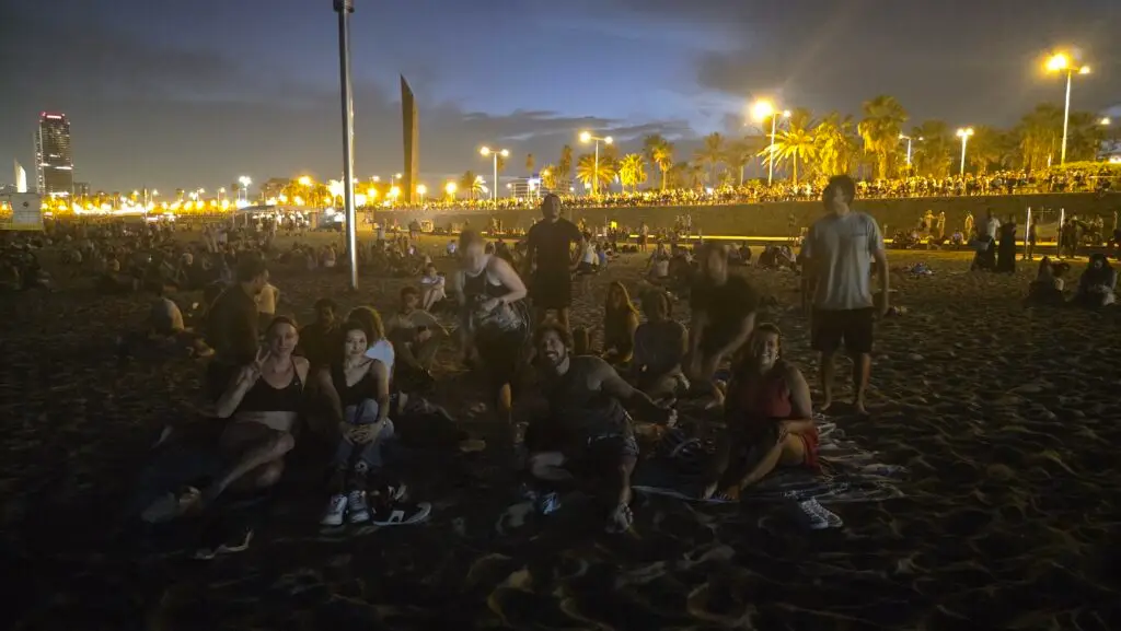 Group of friends watching the full moon over Barcelona at night, enjoying the moonlit skyline together.