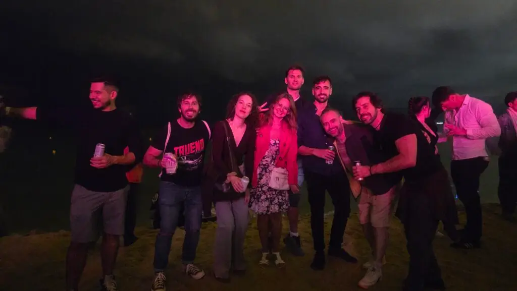 International group celebrating the third night of La Mercè Festival 2025 at Bogatell Beach in Barcelona, enjoying music, drinks, and the night by the sea.