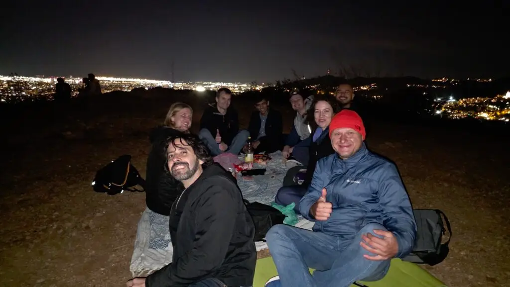 group of people gathered outdoors at night watching the sky during a Leonid meteor shower outing in the hills near Barcelona