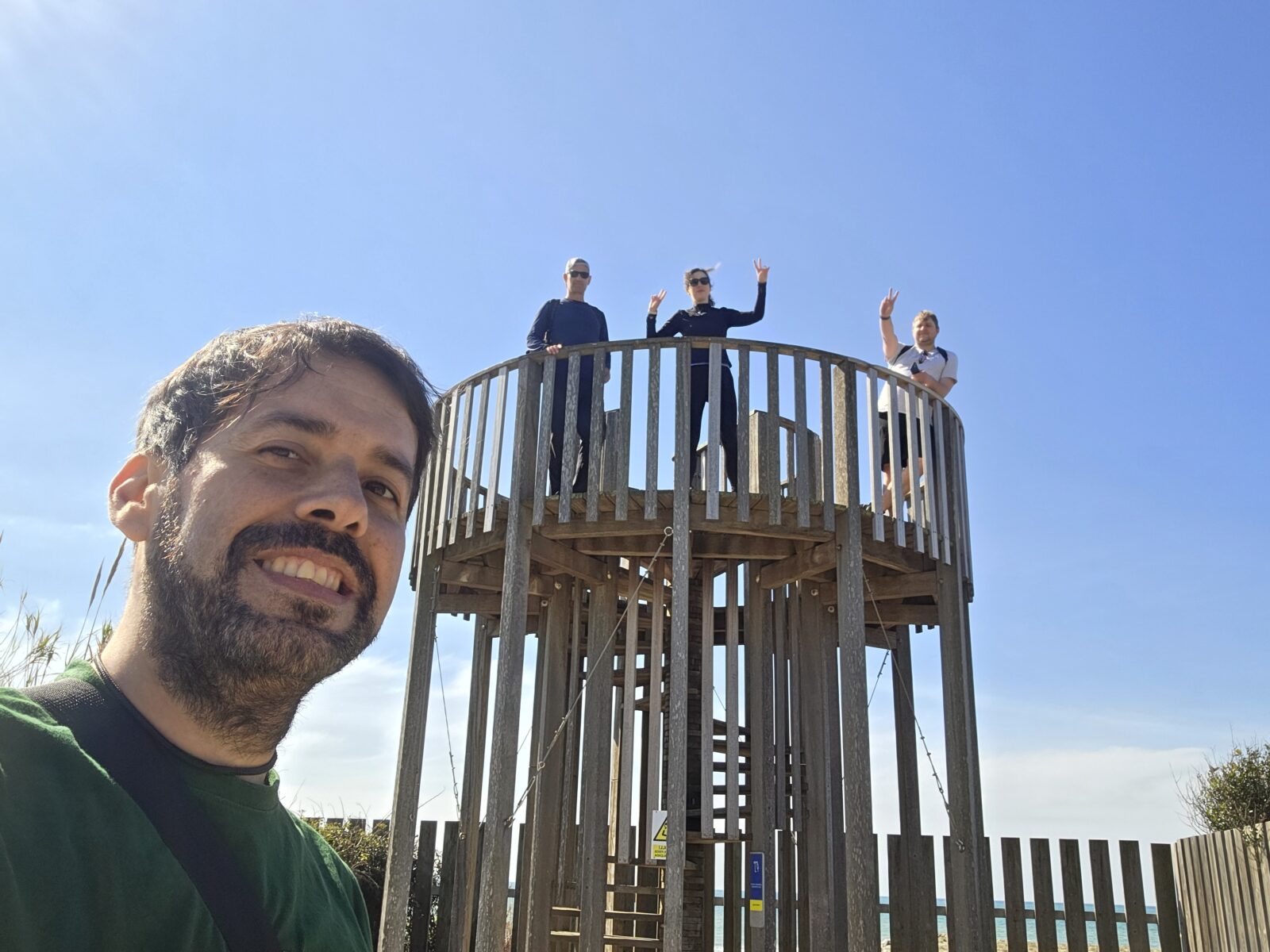 Group of friends on a wooden lookout tower during a sunny bike trip to El Prat beach